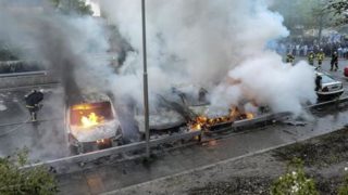 暴動による放火で炎を上げる乗用車（ロイター）